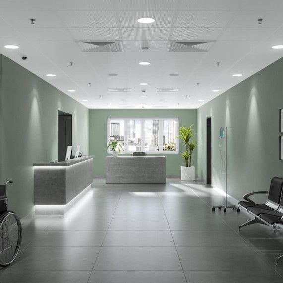 Reception area in a medical facility with gray counters, green walls, and seating.