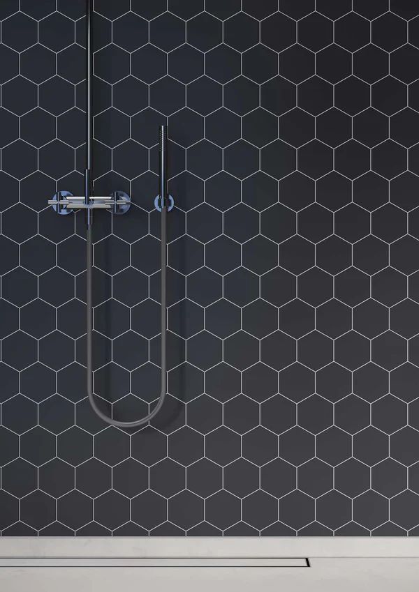 Dark hexagon tile shower wall with silver shower fixture.