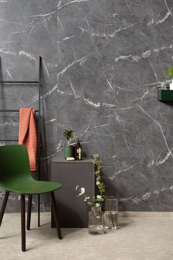 Dark marble-effect wall with green chair, towel on ladder, and plants on a small table.