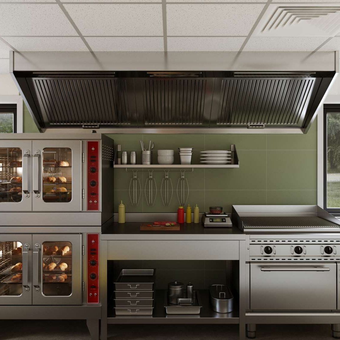 Commercial kitchen with ovens, stove, and ventilation hood.