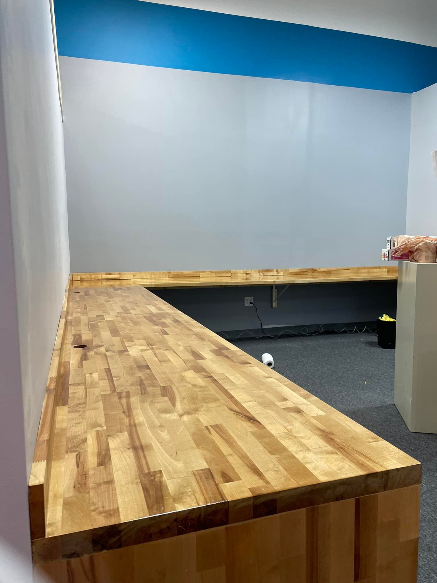Wooden counter extends into a room with gray walls and a blue ceiling.
