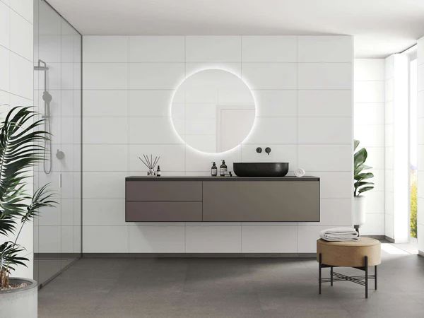Modern bathroom with white tiled walls, floating vanity, circular mirror, and plants.