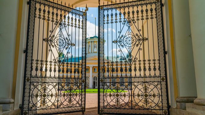 Large wrought iron driveway gate opening to a historic estate.