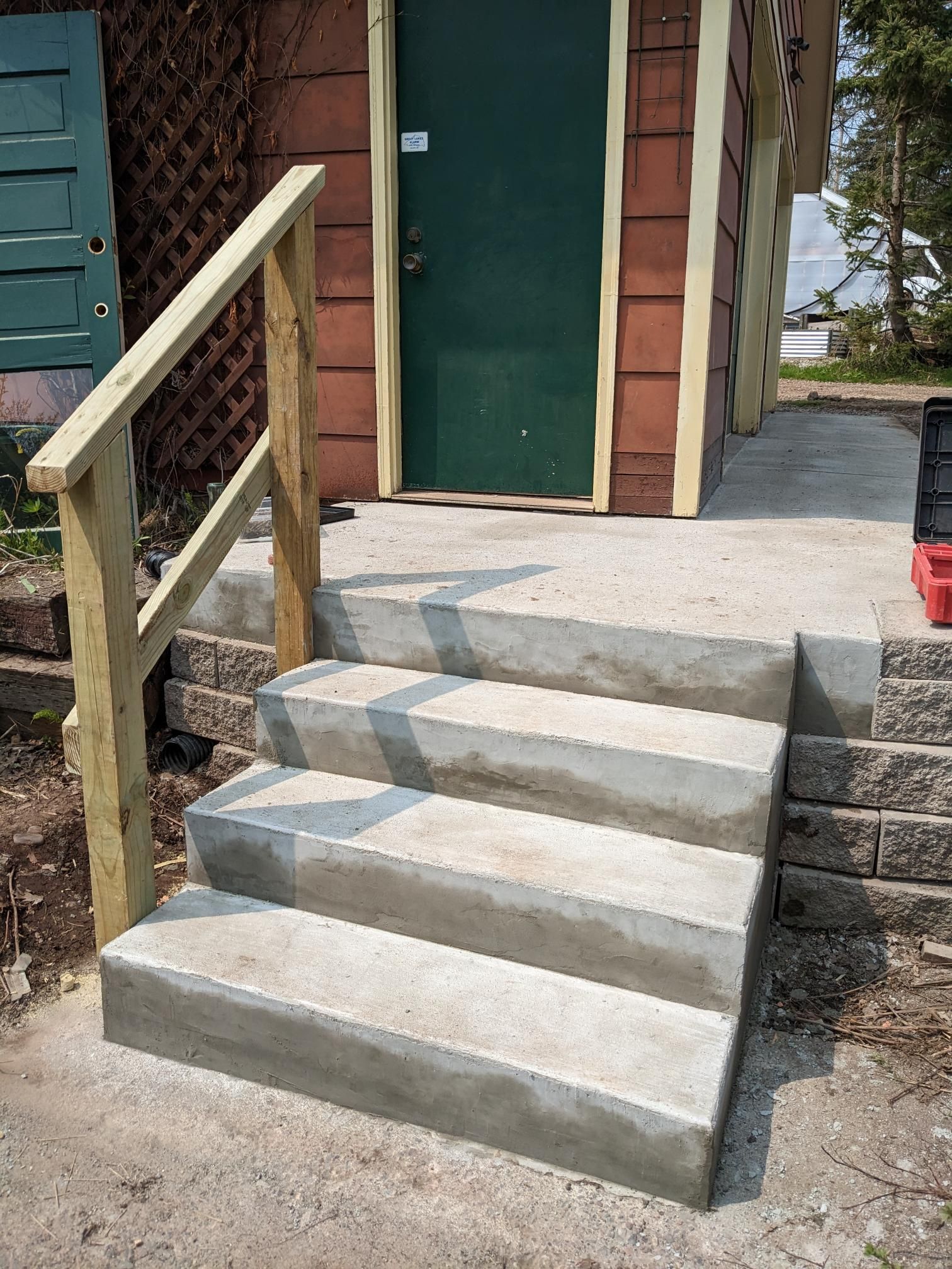A set of concrete stairs leading up to a house with a wooden railing.