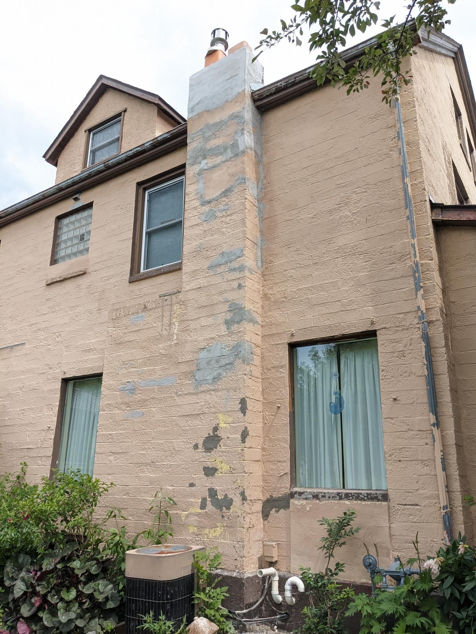 A large brick house with a chimney on the side of it.