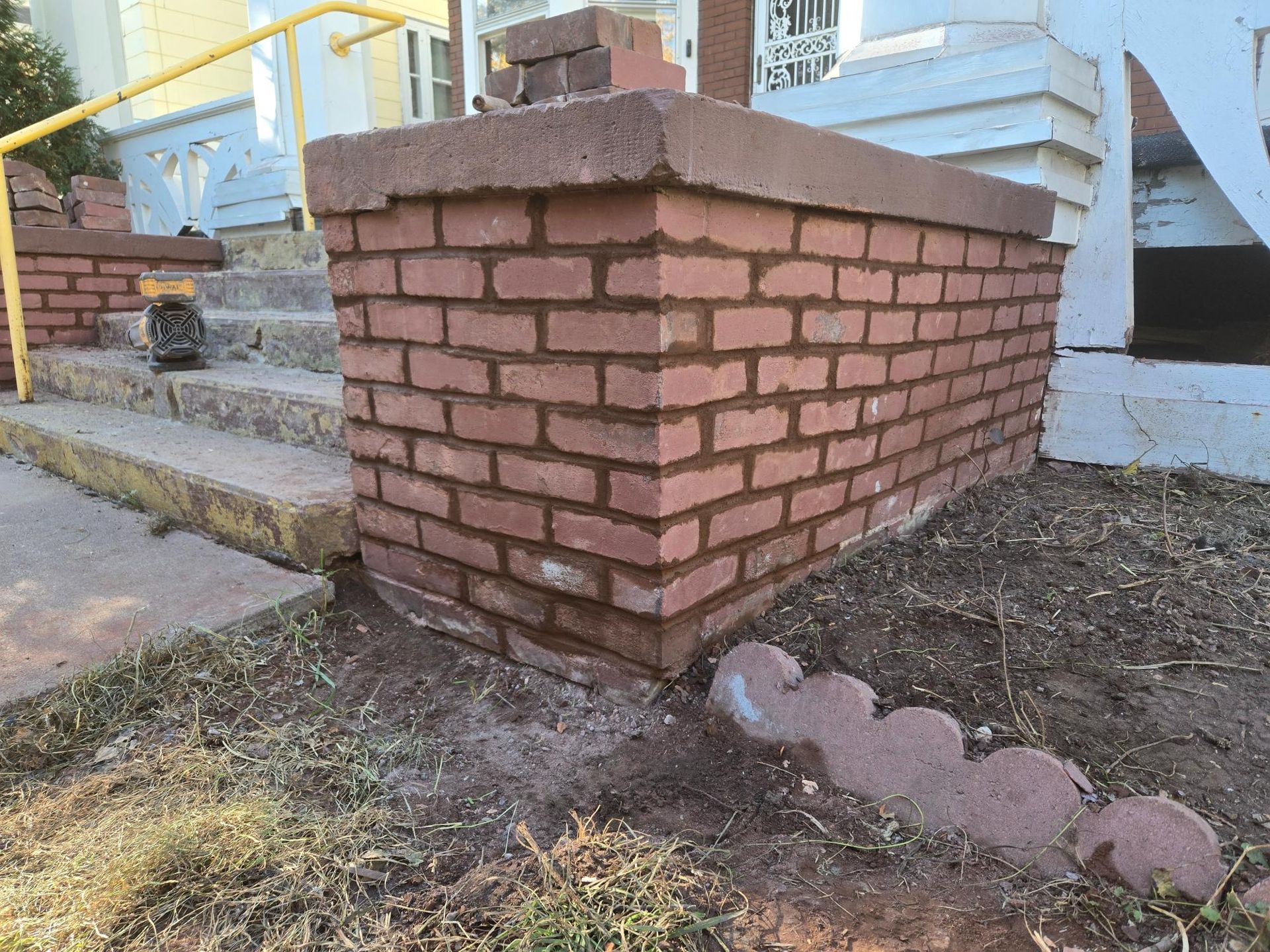 A brick wall is being built in front of a house.