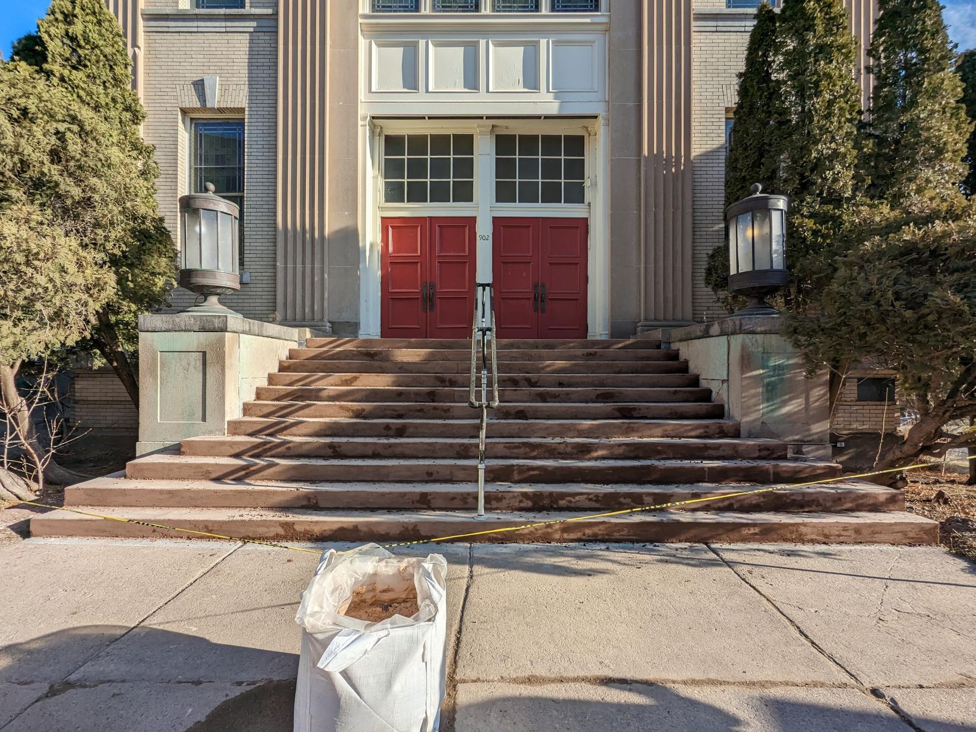 A bag is sitting on the sidewalk in front of a building with red doors