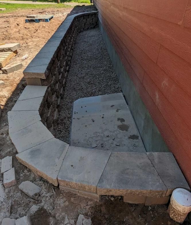 A stone walkway is being built on the side of a house.