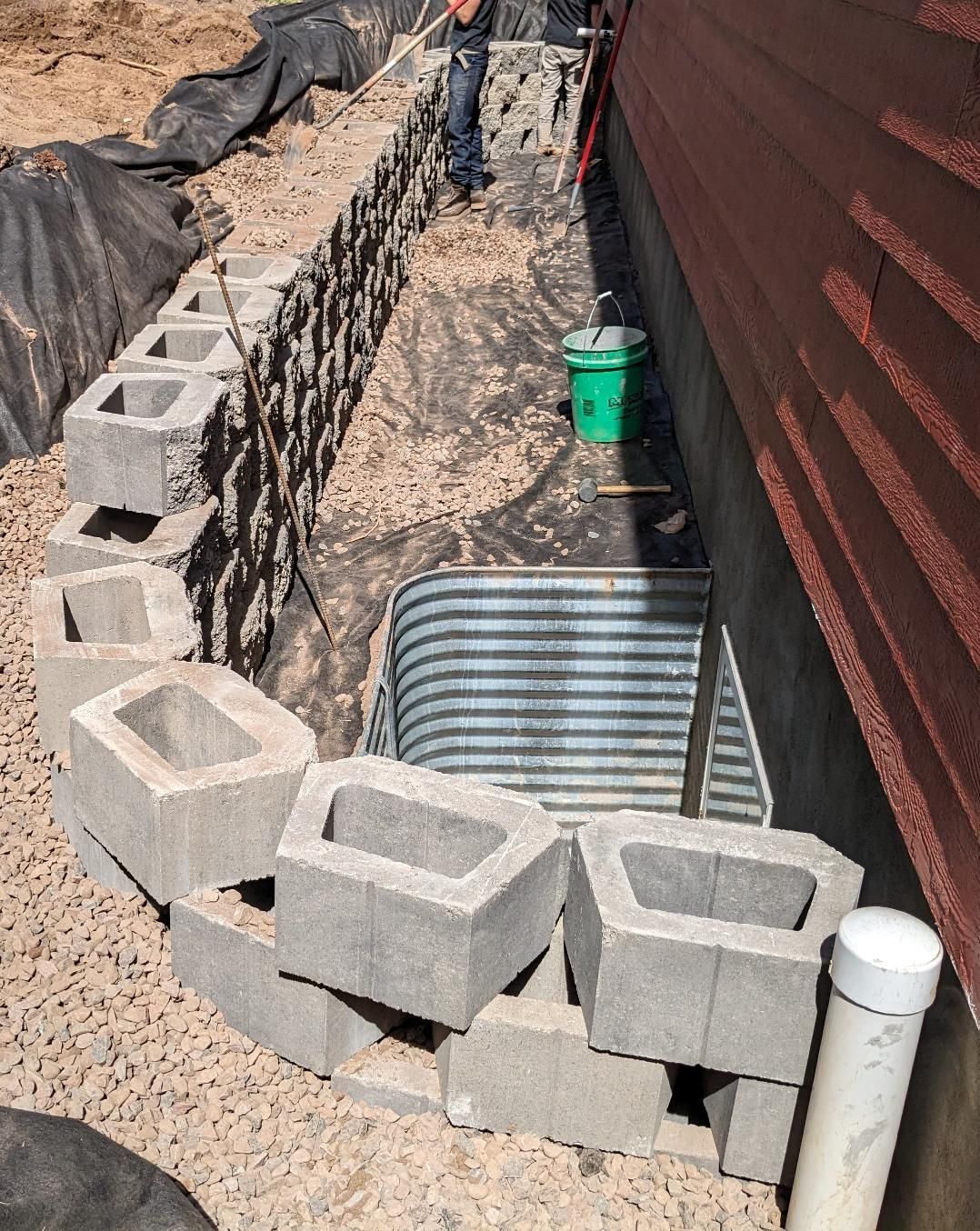 A green bucket is sitting next to a pile of concrete blocks.