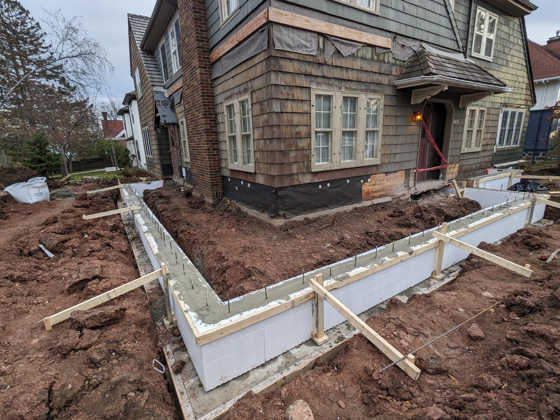 A house is being built with a concrete foundation in front of it.