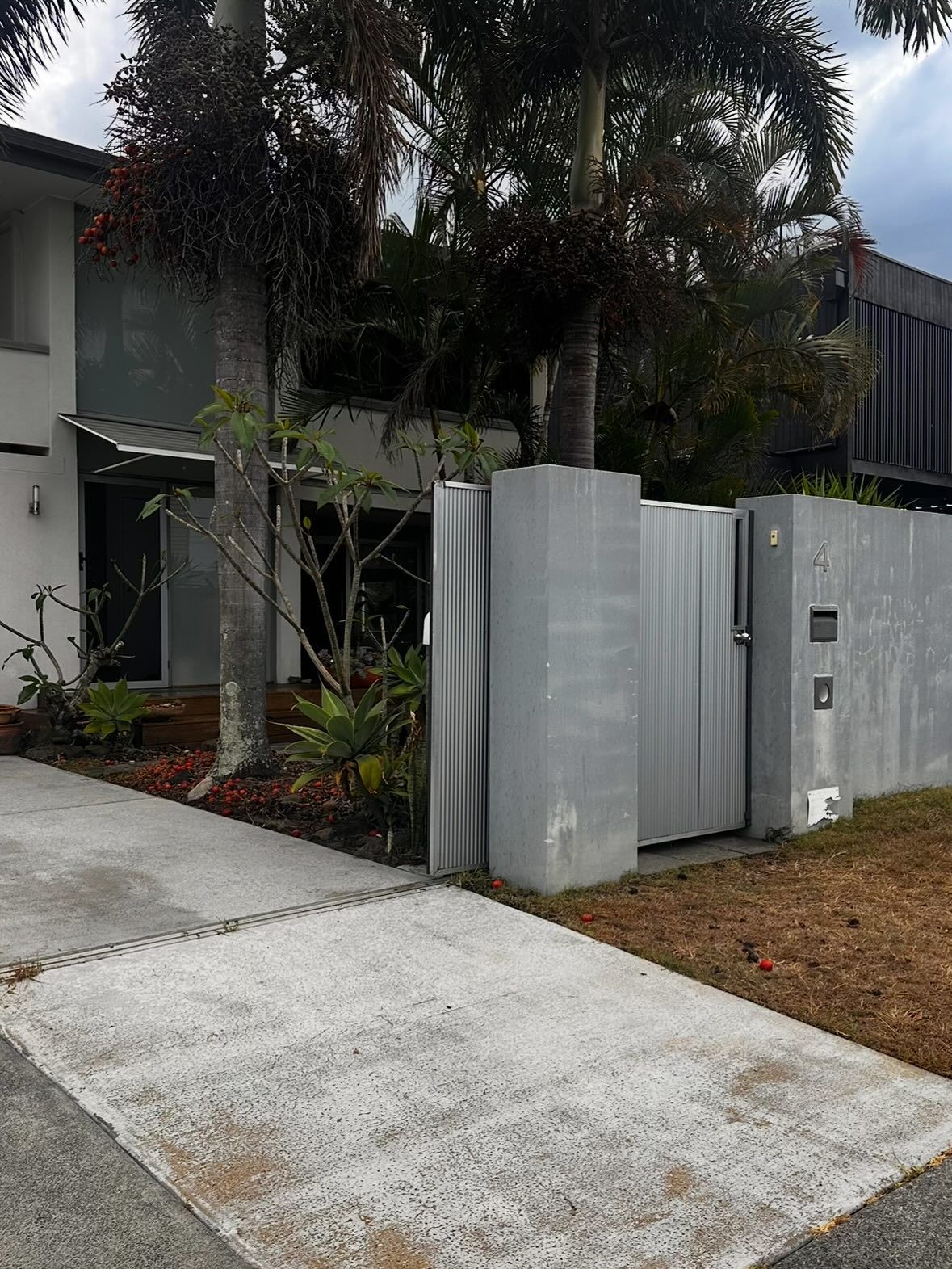 A Modern Two-story Home With a Grey Concrete Wall, Gated Entrance, and a Driveway — Coastal Pressure Solutions in Runaway Bay, QLD
