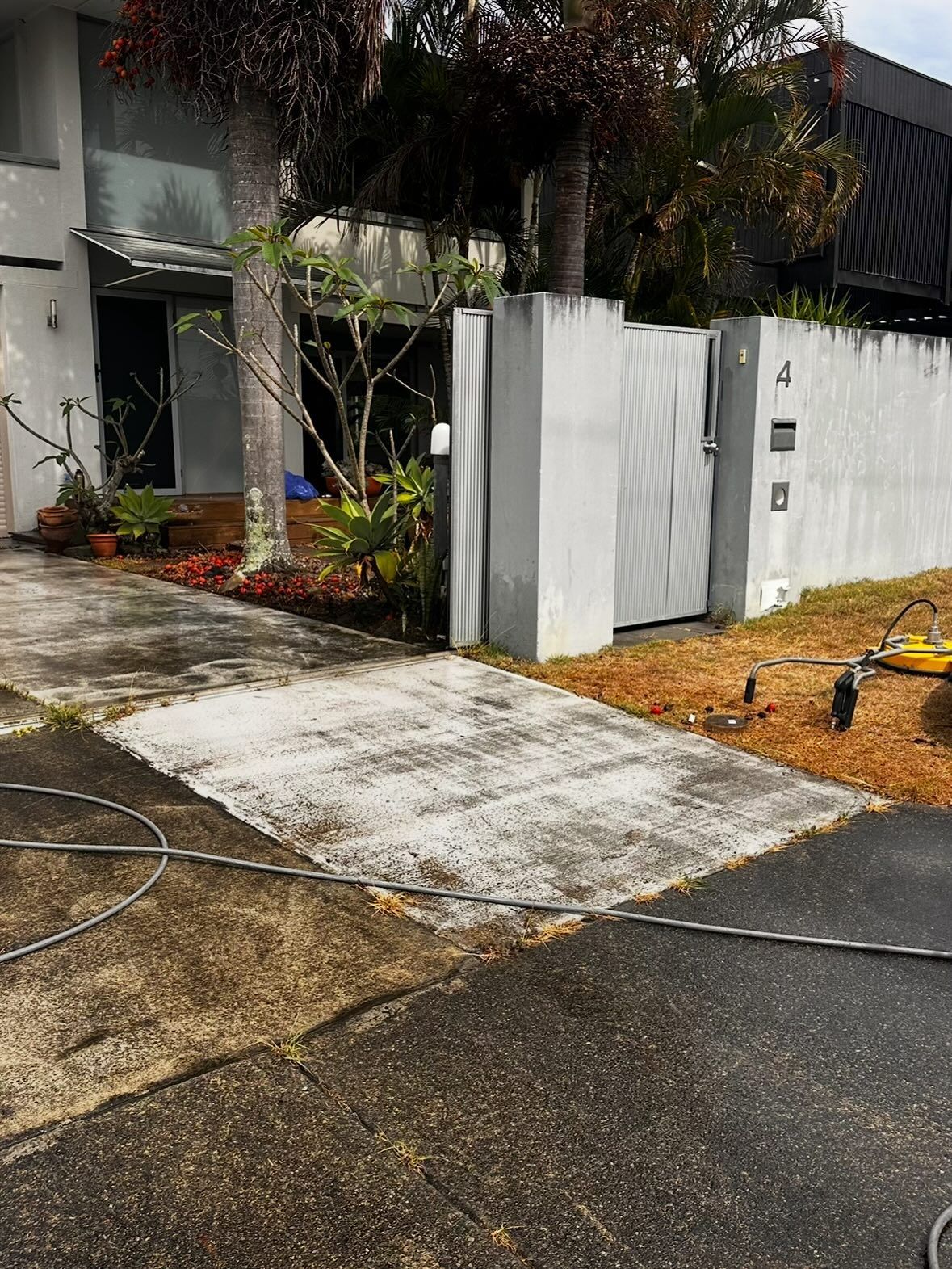 A Residential Driveway Partially Power-washed to Reveal Clean Concrete — Coastal Pressure Solutions in Runaway Bay, QLD