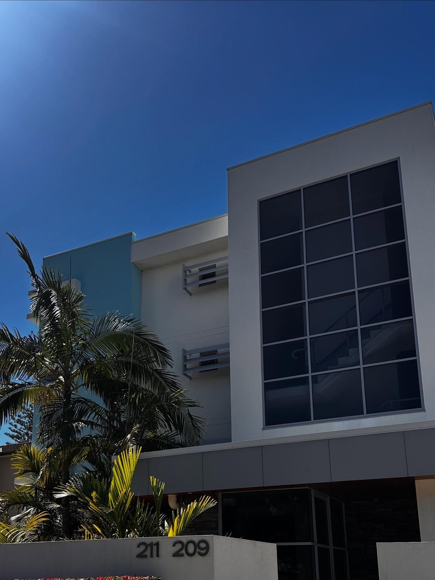 A Modern Three-story Building With White Walls — Coastal Pressure Solutions in Oxenford, QLD
