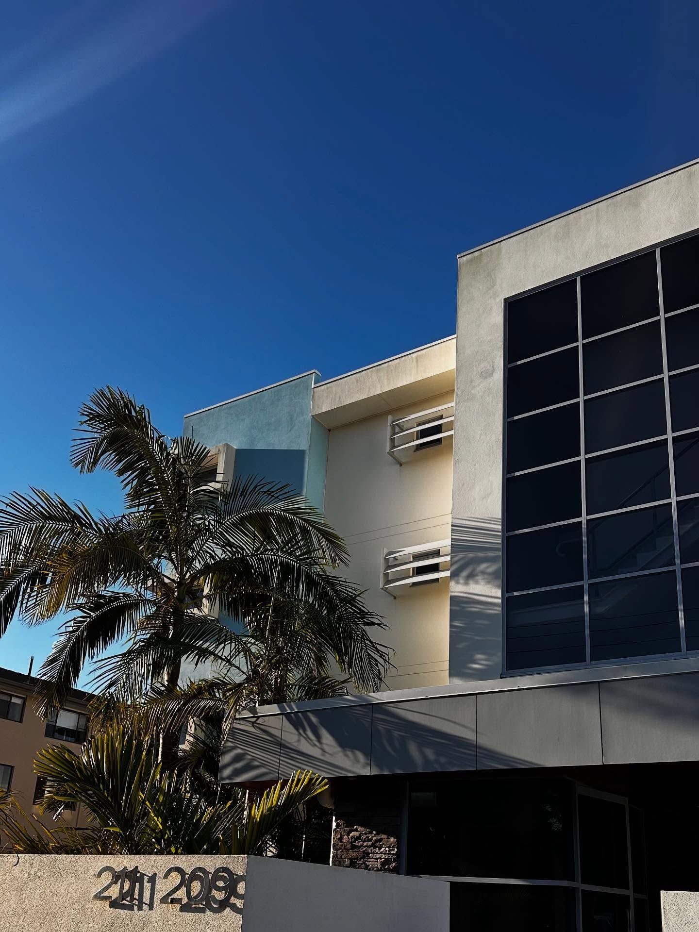 A Modern Building With a Dark Glass Facade — Coastal Pressure Solutions in Oxenford, QLD