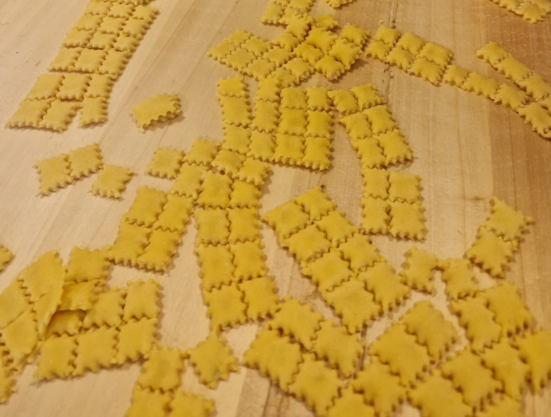 Crackers quadrati sparsi con bordi a zigzag su una superficie di legno chiaro.