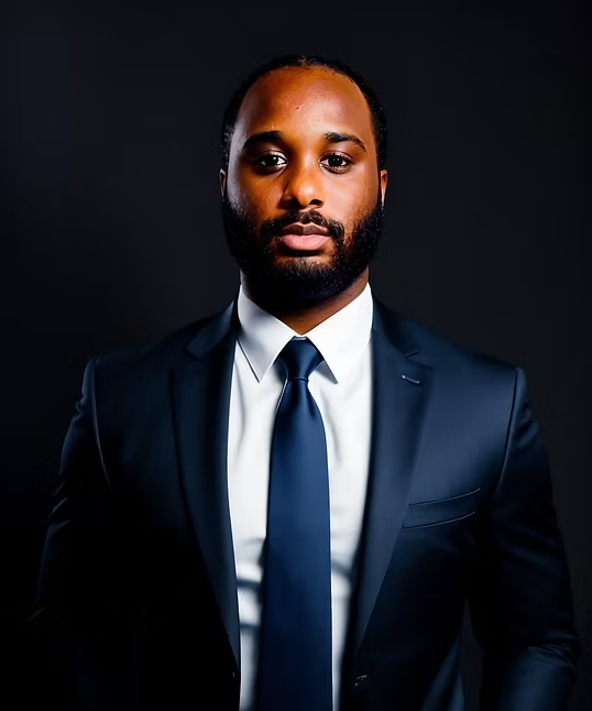 Portrait of a man in a navy suit and tie against a dark background