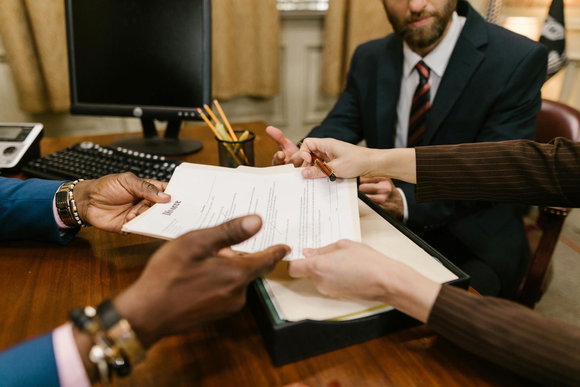 People in a conference room reviewing and signing documents at a wooden table