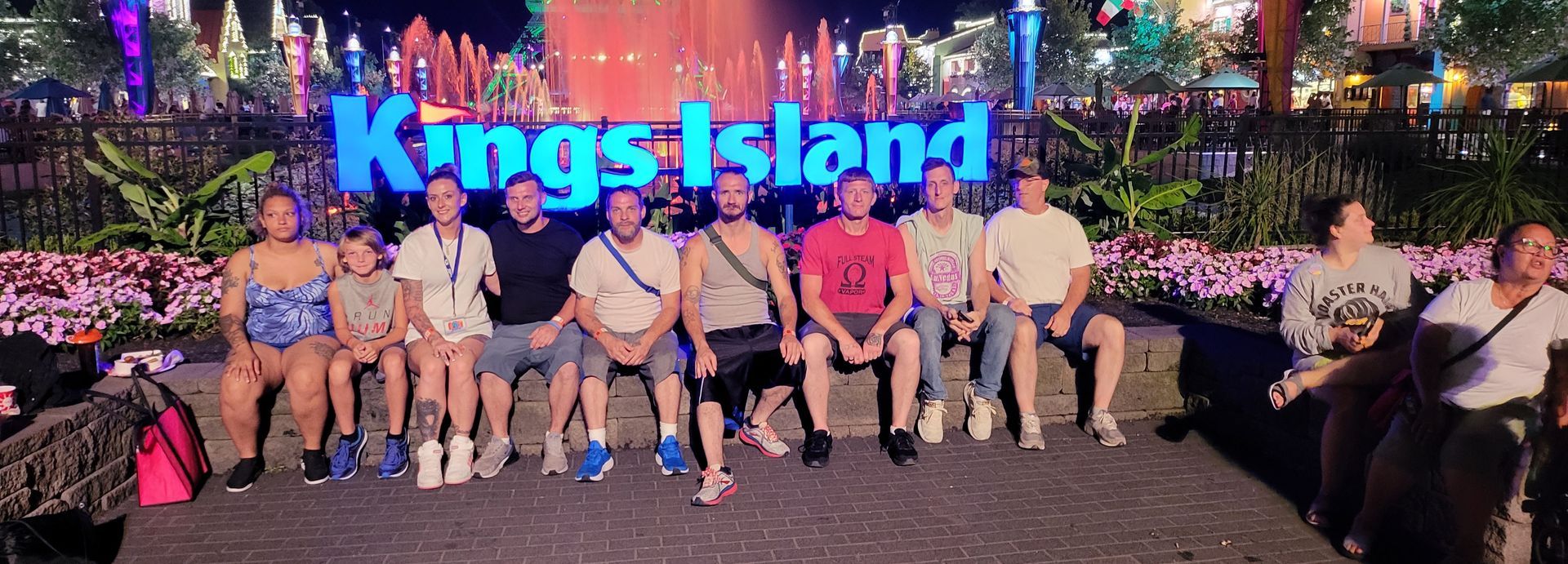A group of people are posing for a picture in front of a sign that says kings island.