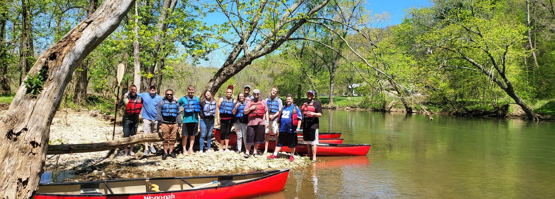 A group of people are standing on a small island in the middle of a river.