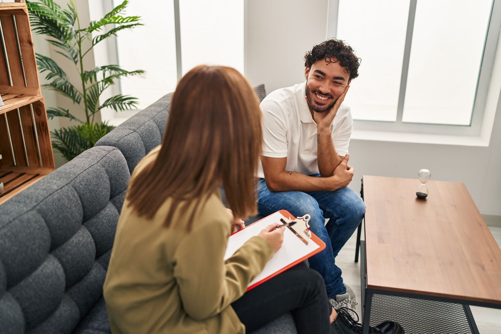 A woman is sitting on a couch talking to a man.