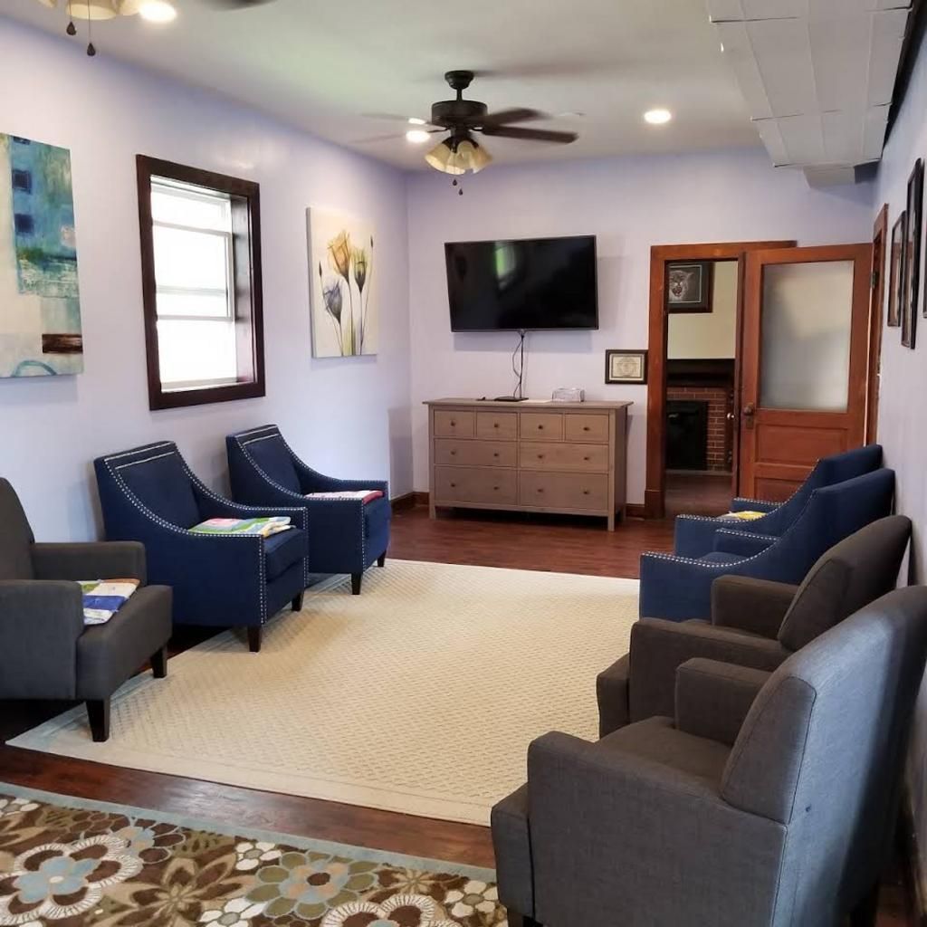 A living room with chairs and a television on the wall
