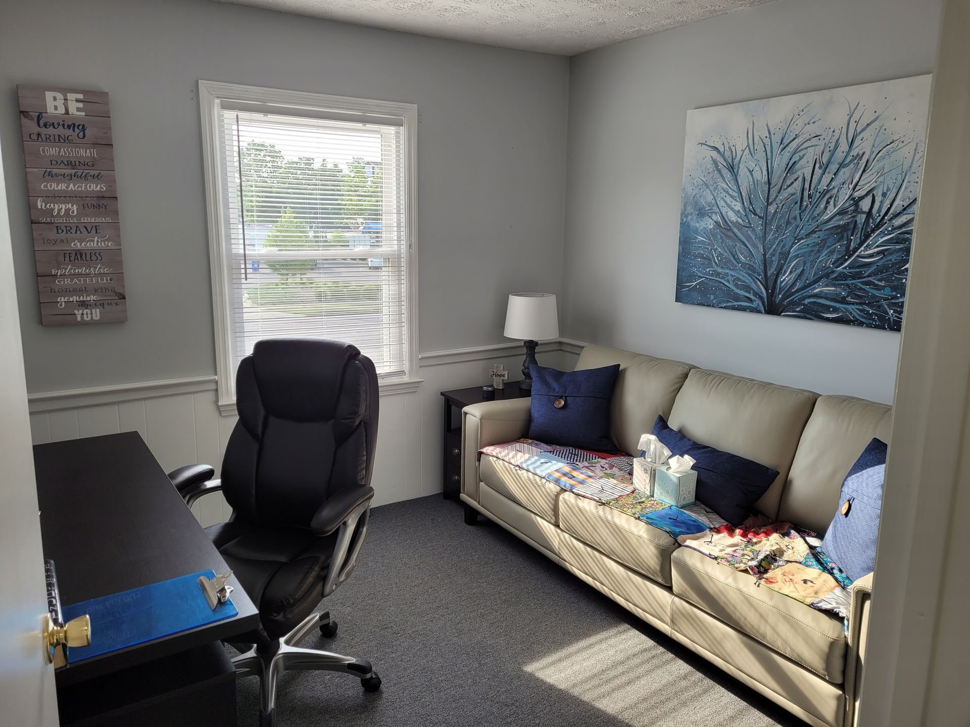 A living room with a couch , chair , desk and window.