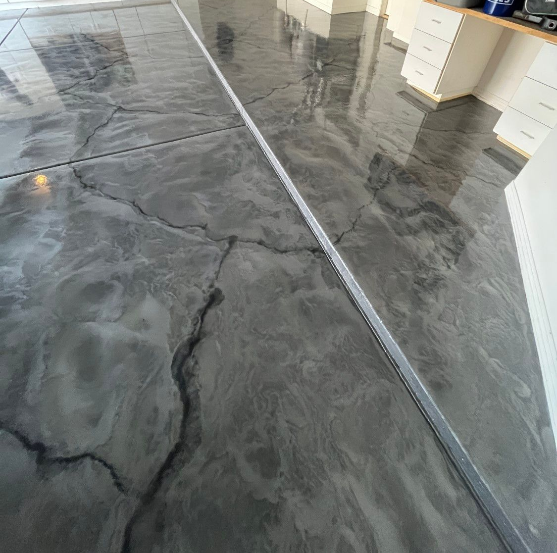 Gray epoxy garage floor with metallic marbling and expansion joint.