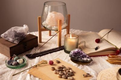 Crystals, candle, incense, and herbs arranged on a white cloth in a calming ritual setup
