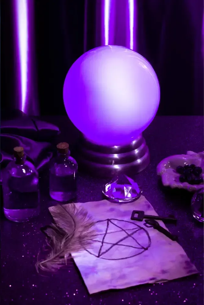 Purple crystal ball on a table with ritual items and a pentagram diagram under violet lighting