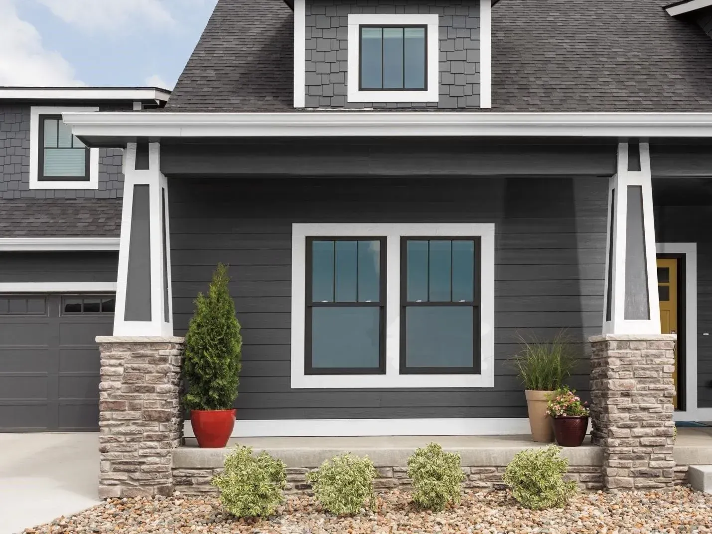 A gray house with a porch and two windows