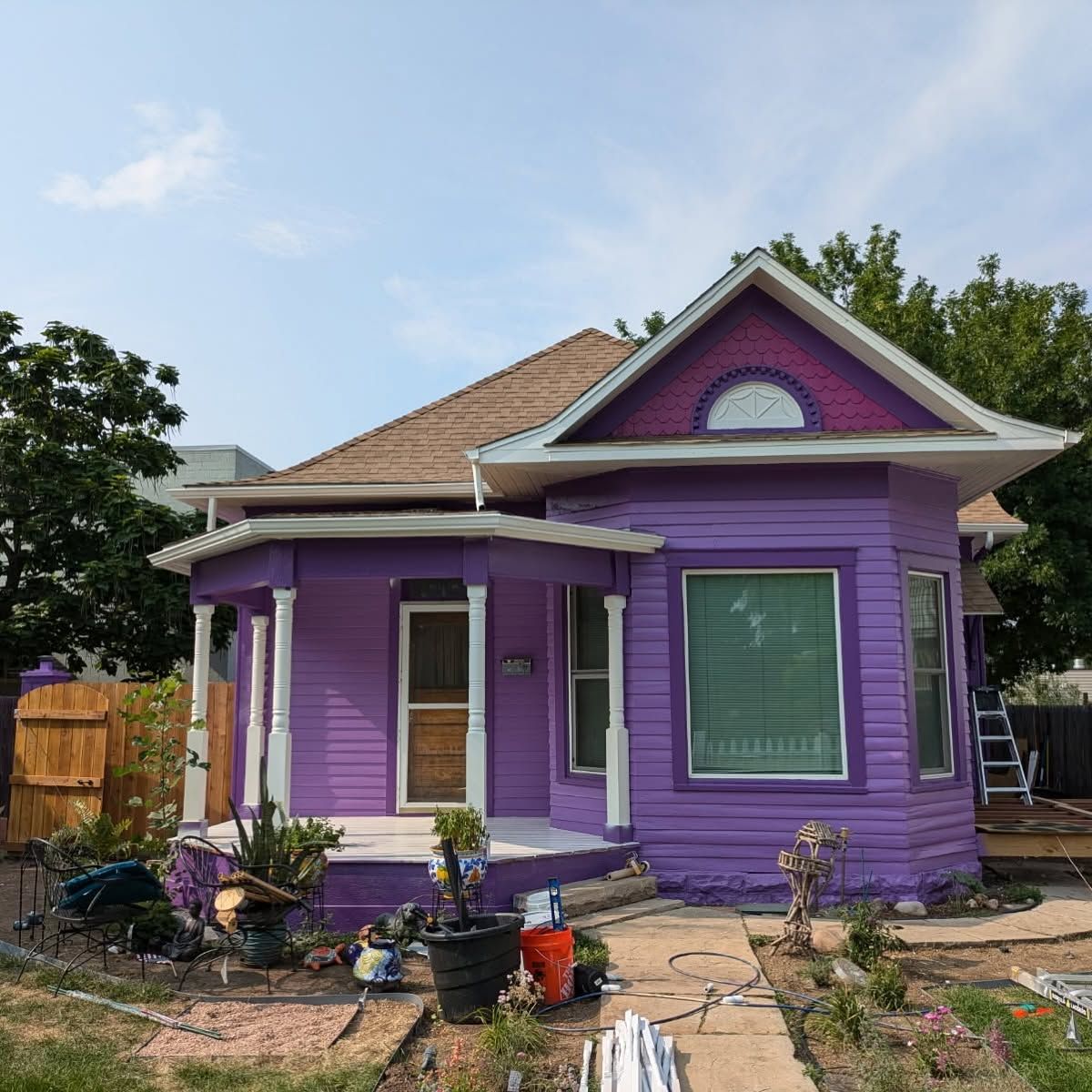 Purple house with white trim and a front yard under clear sky