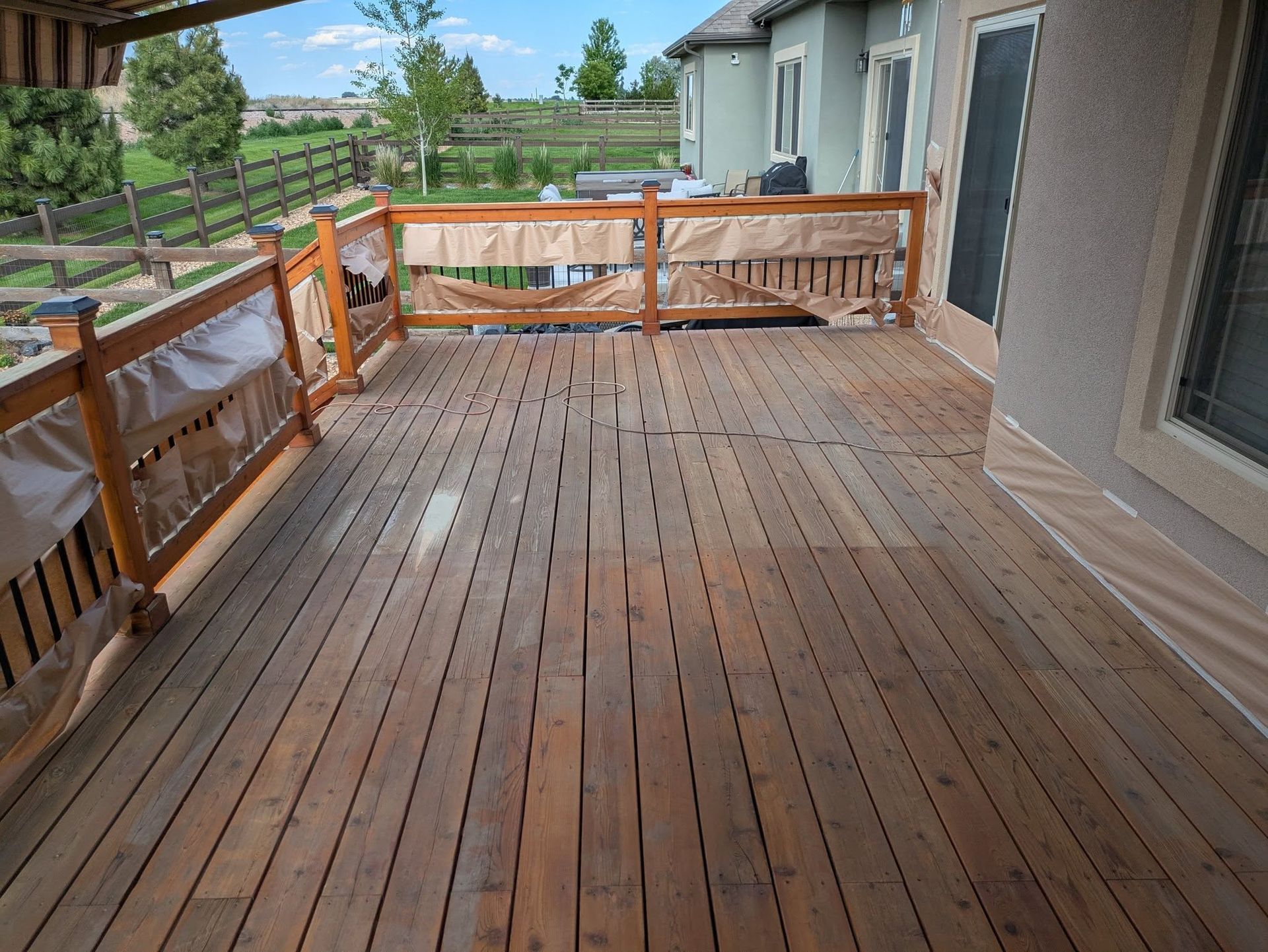 Wooden backyard deck with railings and a view of a grassy yard and trees