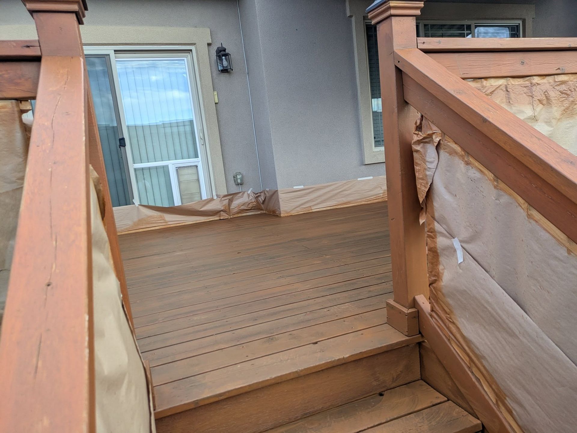 Wooden porch ramp with railings leading to a glass door on a house exterior