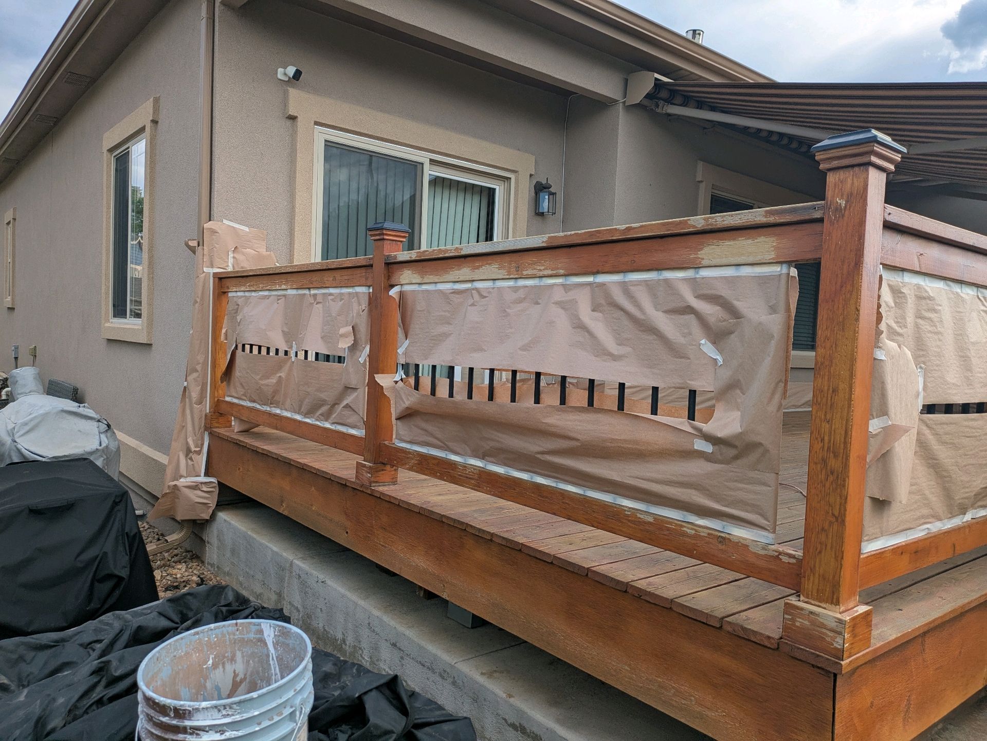 House exterior with a wooden deck railing covered in protective plastic sheeting during construction or repair