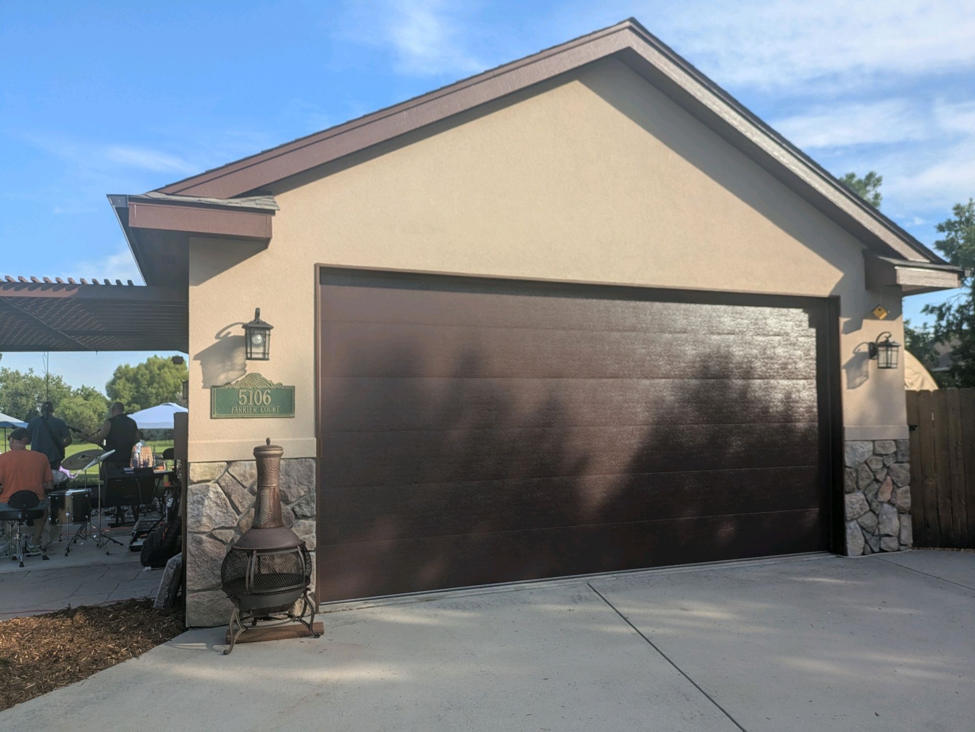 Suburban garage with dark brown door, beige exterior, and concrete driveway under a blue sky