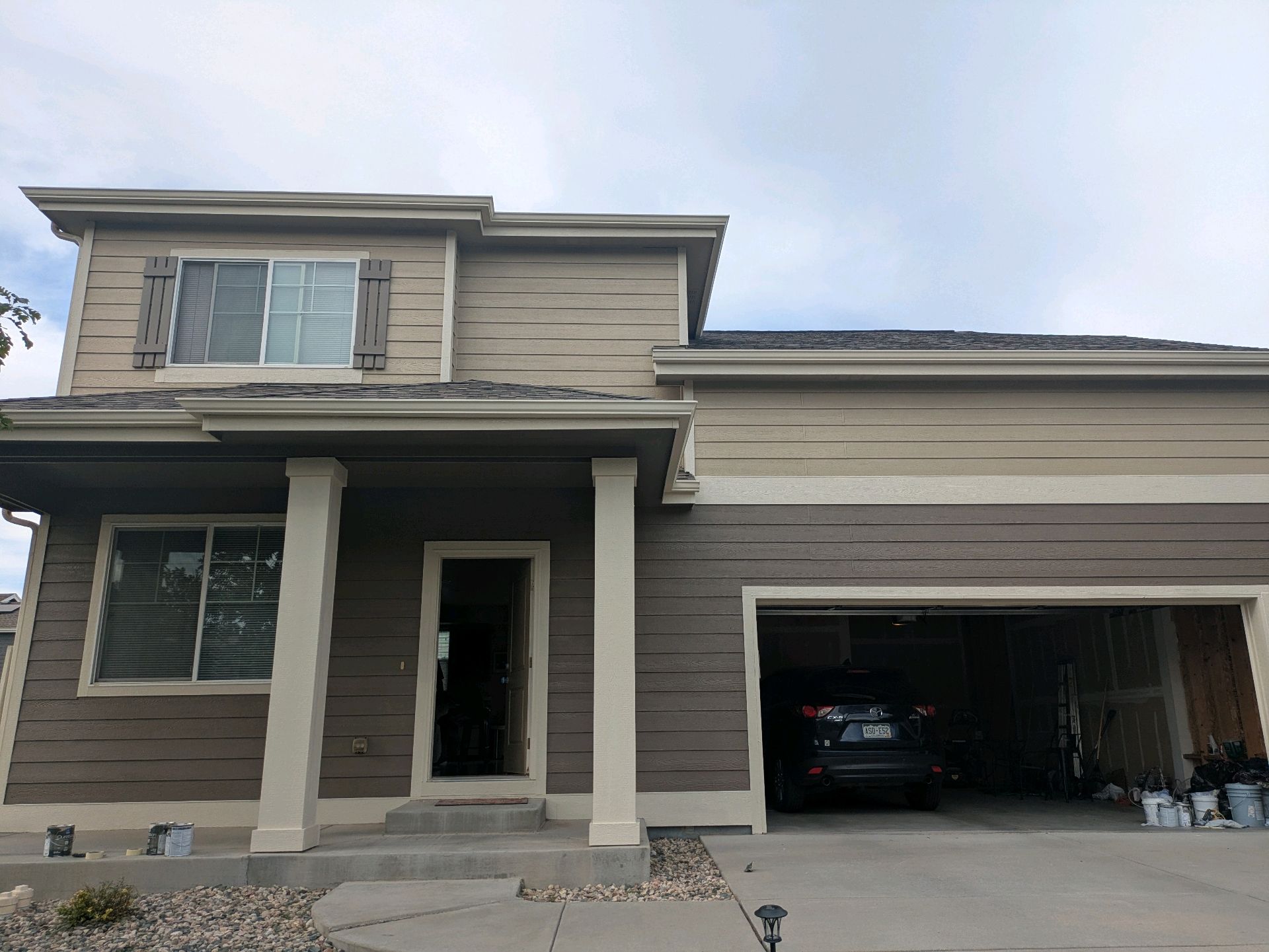 Two-story beige house with white columns and an open garage