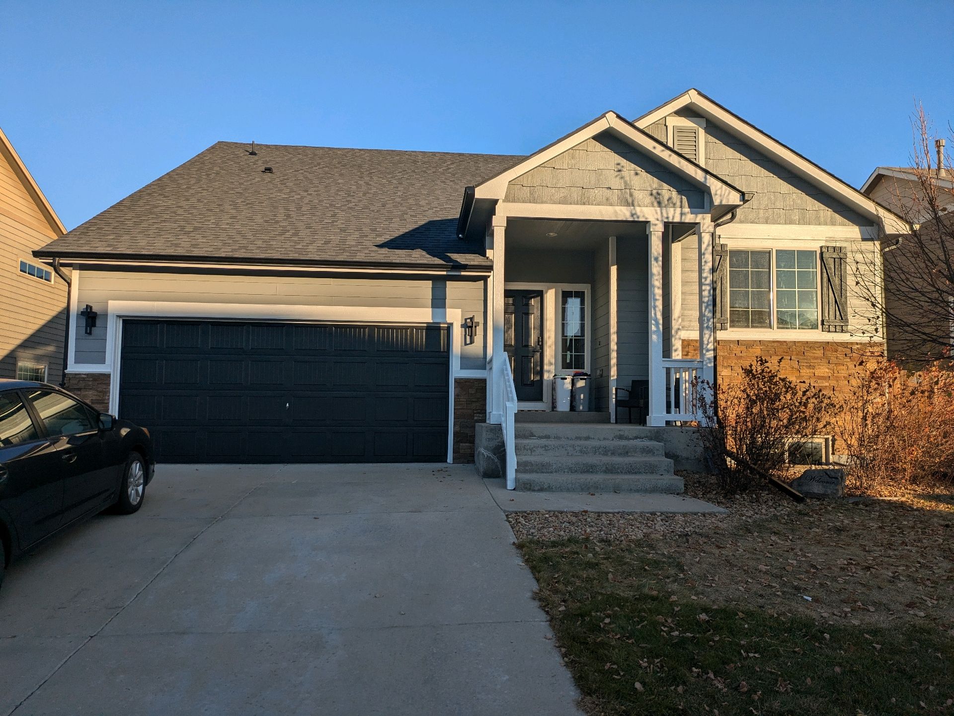 Suburban house with two-car garage, front porch, and concrete driveway at sunset