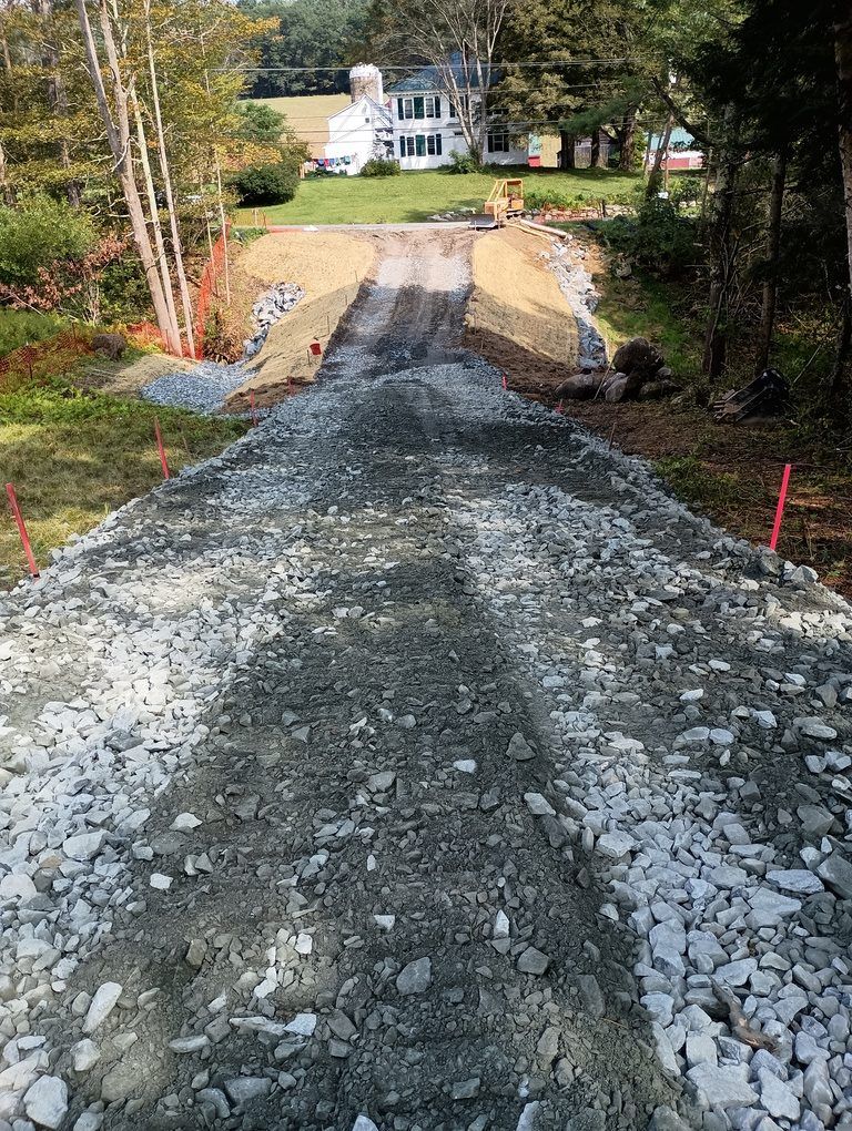 A gravel road is being built in front of a house.