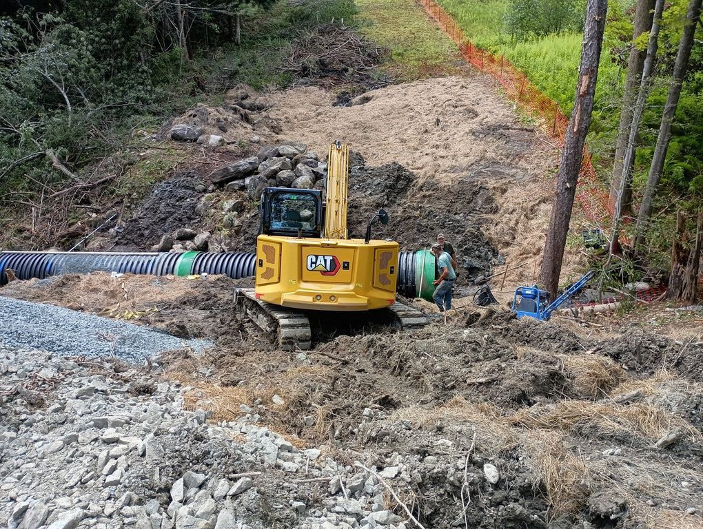 A yellow excavator is sitting on top of a pile of dirt.
