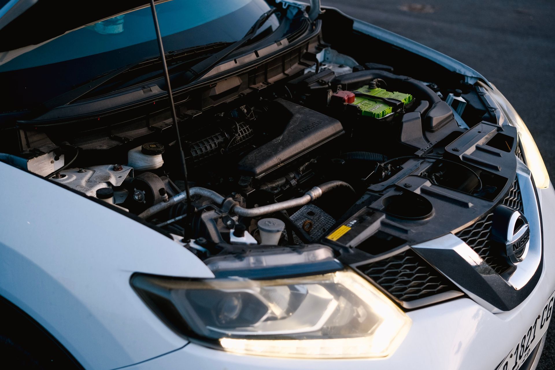 White car with hood open, showing the engine bay and front headlight.