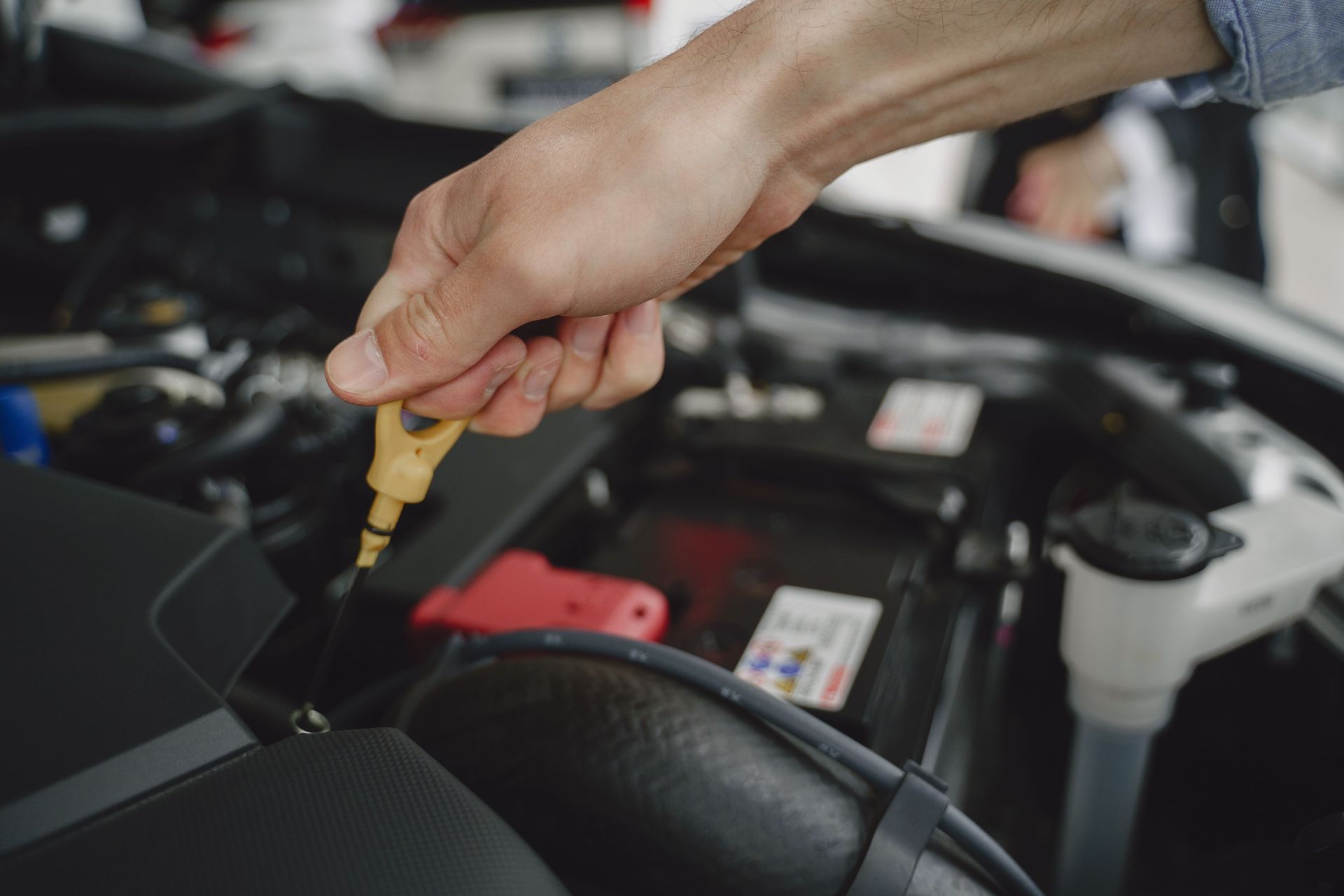 Hand checking engine oil with a dipstick in a car engine bay
