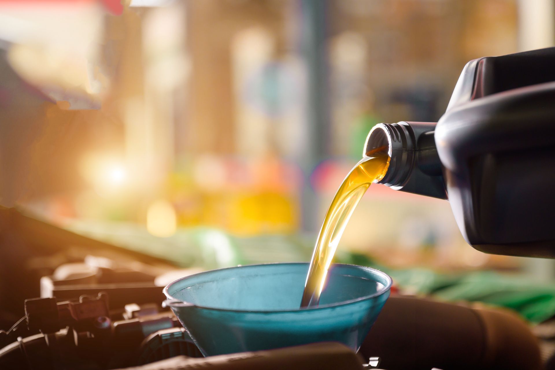 Cooking oil being poured from a bottle into a blue bowl beside a stovetop