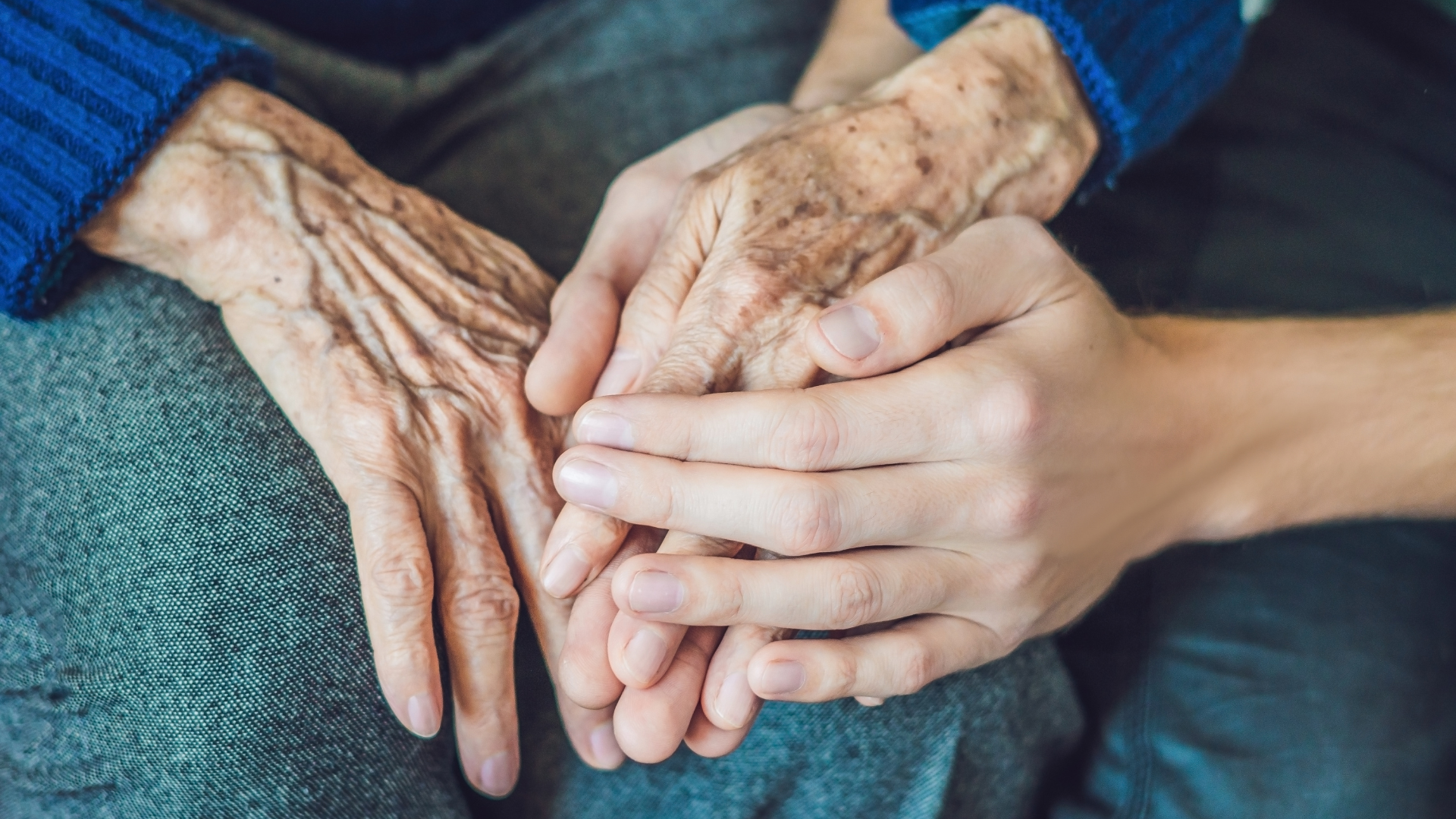 Young caregiver comforting an elderly woman in a bright kitchen