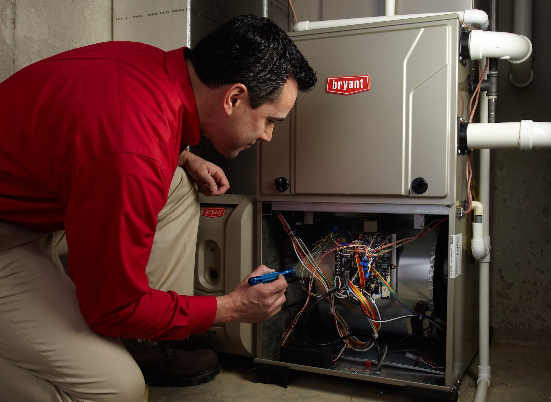 A man in a red shirt is working on a furnace.