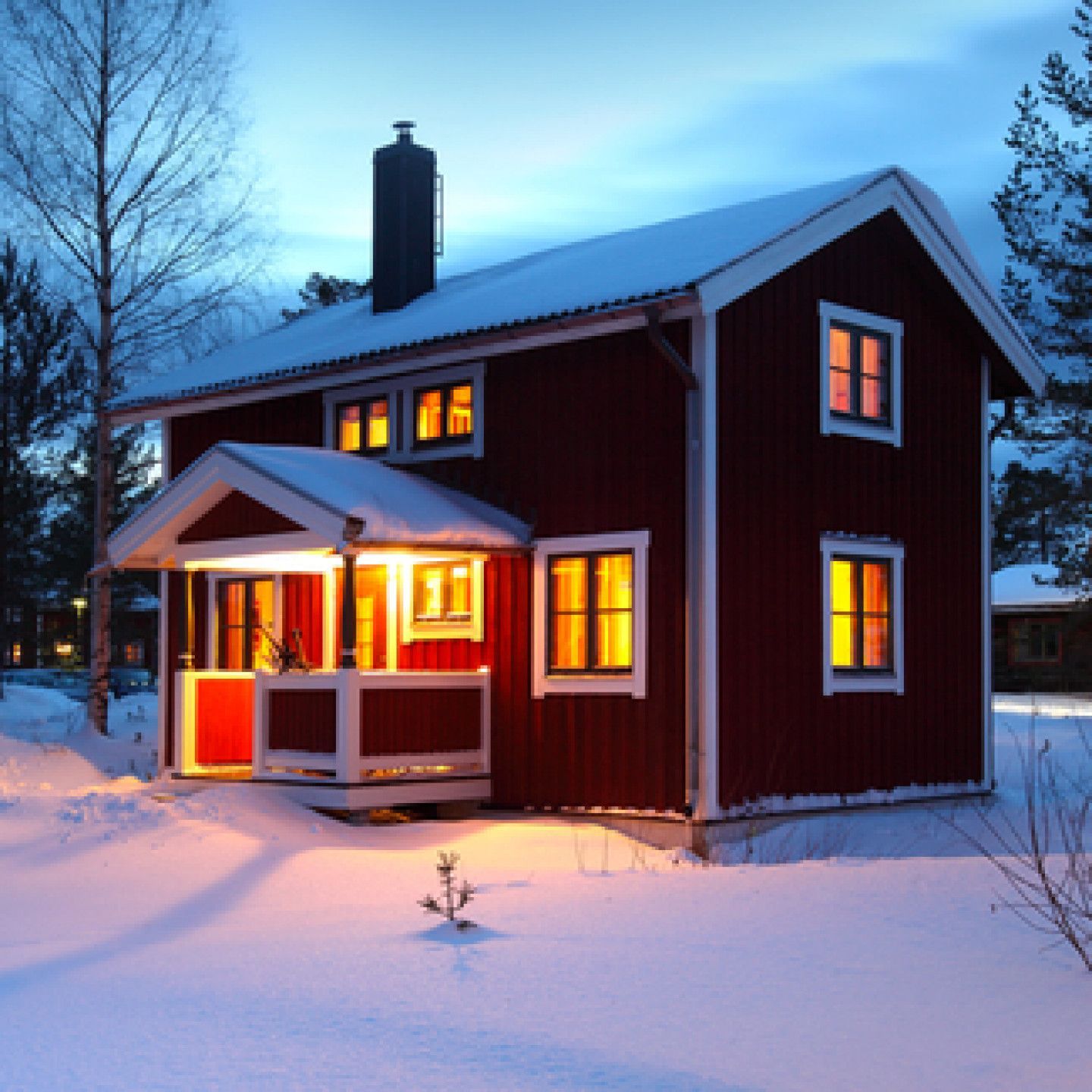 A red house is lit up in the snow at night