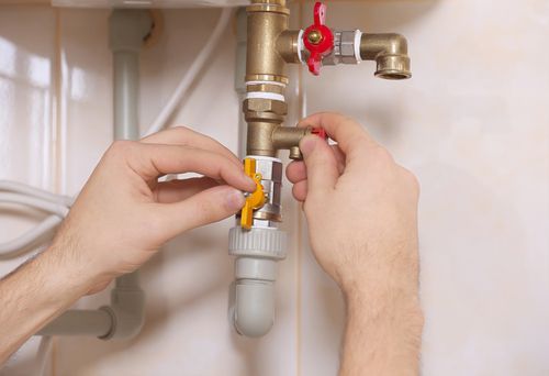 A man is fixing a faucet in a bathroom.