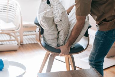 Person adjusting a white blanket in a cushioned chair in a bright room