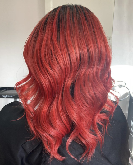 Long wavy red hair with darker roots, viewed from the back against a light background