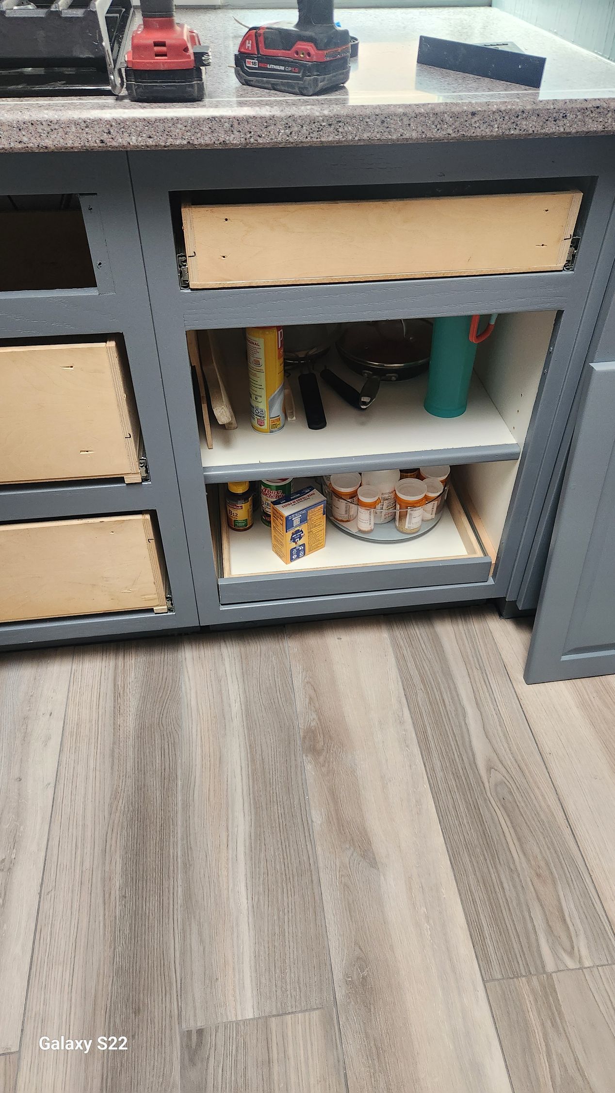 Kitchen cabinet under construction with tools on countertop, showing shelves and cabinet facings.