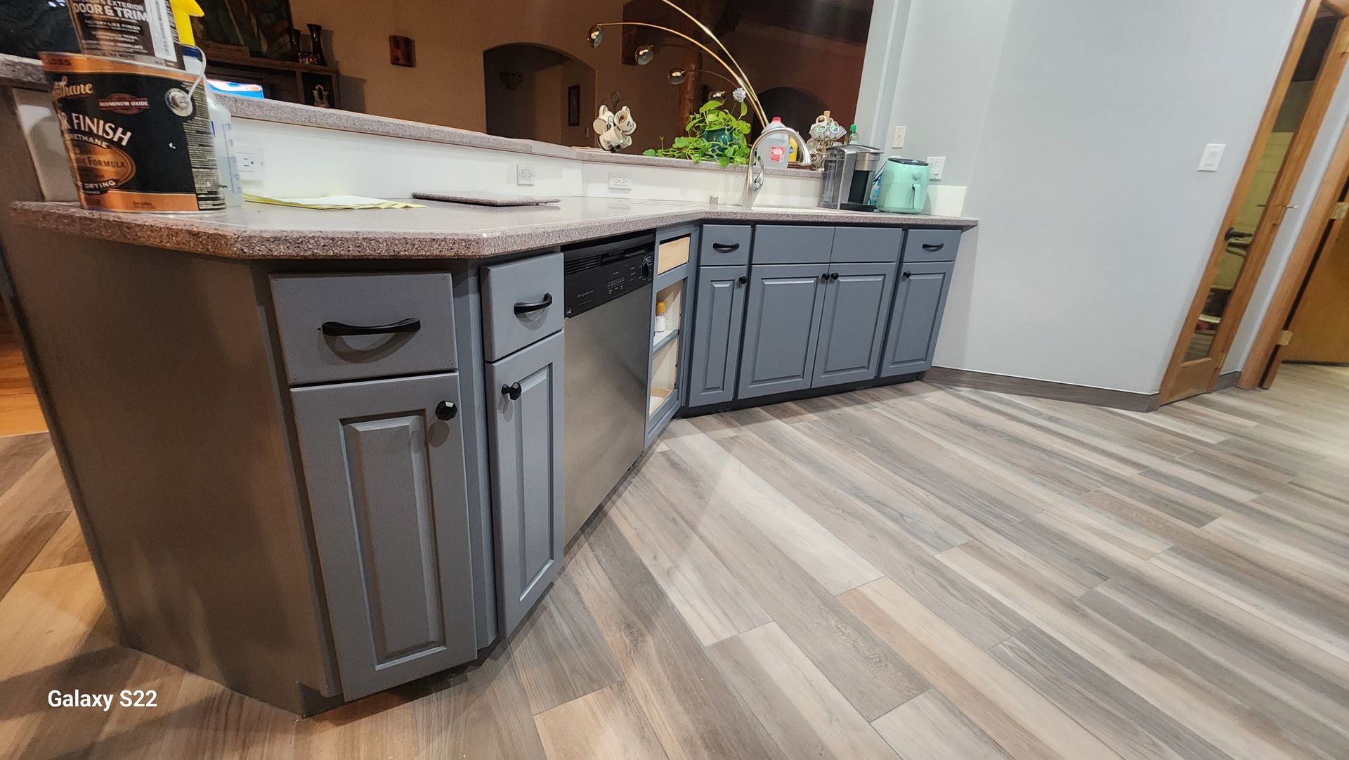 Gray kitchen cabinets with stainless steel appliances, granite countertop, and wood-look flooring.